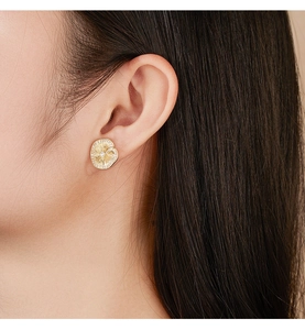 Detail of golden S925 silver petal earrings with sparkling zircons on female model