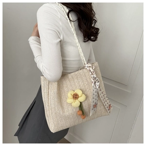 Detail of woven straw bucket bag with floral decor and silk scarf handle accent
