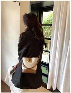 Detail of canvas and brown PU leather bucket bag with gold hardware worn by a model