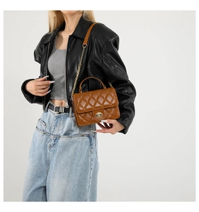 Sac bandoulière matelassé marron avec chaîne dorée porté par un mannequin