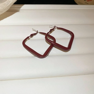 Macro shot of dark red geometric square earrings with a matte painted metal finish