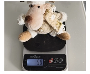 Weight measurement of a plush reindeer ornament on a scale showing exactly 50g