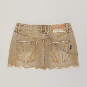 Détail d'une jupe en jean marron vintage avec ourlet effiloché et chaîne de taille en métal