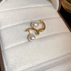 Detailed close-up of golden metal earrings with white pearls on a velvet jewelry box
