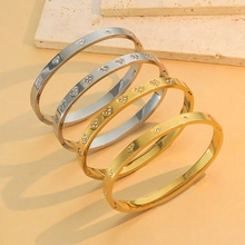 Detail view of gold and silver stainless steel bangles with screw motif on stone plate