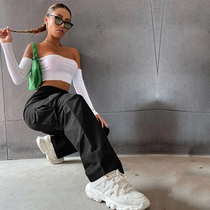 Détail d'un pantalon cargo noir à grandes poches et d'un haut bandeau blanc court