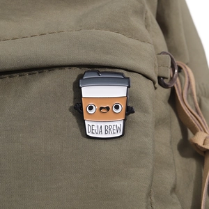 Détail du pin's émaillé café Deja Brew épinglé sur un sac en toile verte