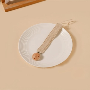 Détail d'attache-tétine en tissu de coton beige et bois de hêtre naturel pour bébé
