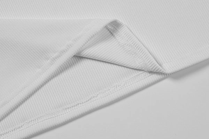 Gros plan détaillé sur la texture en maille côtelée blanche et les coutures de l'ourlet