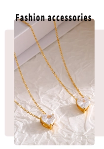 Macro detail of heart-shaped zircon pendant on a gold chain over white paper