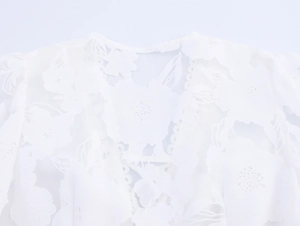 Detailed close-up of white floral lace embroidery and hollow-out mesh texture on dress