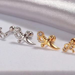 Detailed view of silver and gold dagger stud earrings with sparkling zircon inlay
