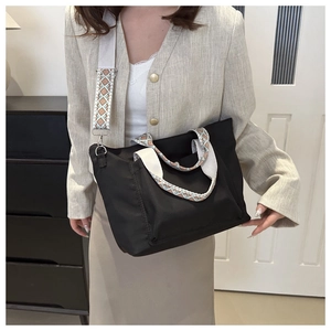 Detail of black nylon tote bag featuring a wide patterned strap and spacious interior