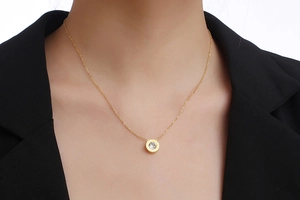 Close-up of a gold solitaire necklace with Roman numerals worn by a model