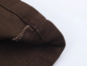 Dettaglio del tessuto twill marrone scuro con cuciture sui bordi del set di jeans