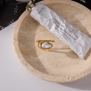 Detailed view of an 18K gold stainless steel ring with a baroque pearl on a stone tray