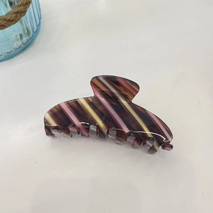 Detailed close-up of a large acetate claw clip with brown and pink diagonal stripes