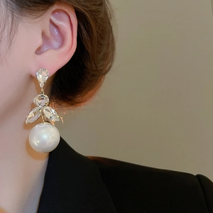Detail of luxury pearl earrings with crystal accents on a model in elegant style