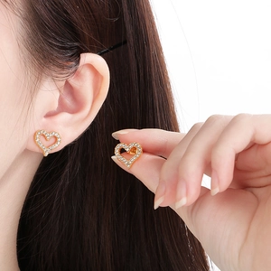 Detail view of gold heart stud earrings with sparkling pavé micro diamonds on a model