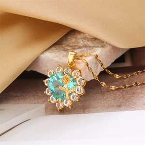 Macro shot of gold heart necklace featuring a light blue gemstone with rose floral pattern