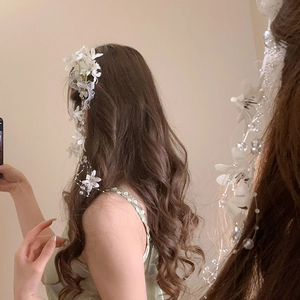 Detail view of white fabric flower hair clip with lace and long pearl tassel fringe