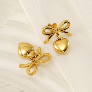 Détail de boucles d'oreilles nœud dorées avec cœurs sur un fond en tissu blanc