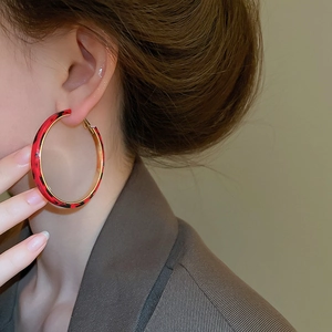 Close-up of red leopard print hoop earrings with gold trim worn by a model