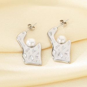 Detailed view of silver irregular geometric pearl earrings on elegant silk fabric