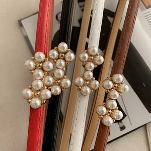 Detail of four thin leather belts with gold buckles and pearls in red, black, white, brown