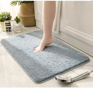 Close-up of soft thick light blue bathroom mat showing water absorption and plush texture
