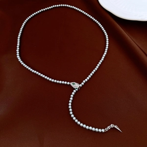 Close-up of grey pearl necklace featuring a green zircon snake head and tail pendant