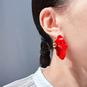 Exaggerated red petal earrings with gold beads shown in a stylish minimalist ear model view