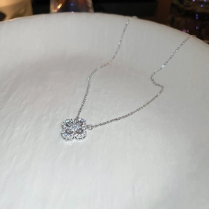 Detailed view of silver clover pendant necklace with sparkling cubic zirconia on a white plate