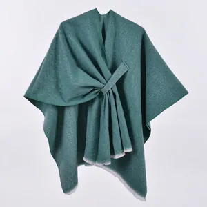 Detailed view of dark green knit shawl featuring diagonal strap design and woven texture
