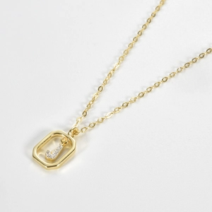 Macro detail of a gold octagon pendant with a sparkling zircon letter J on a cable chain