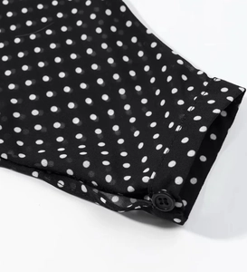Detailaufnahme der schwarz-weiß gepunkteten Chiffon-Manschette mit einem Knopf-Detail