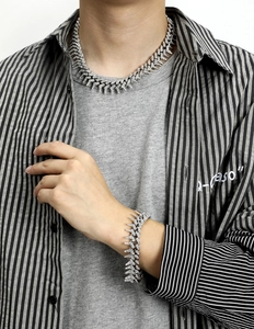 Close-up of iced out silver thorn Cuban link necklace and bracelet set on male model