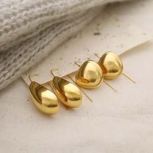 Polished 18K gold-plated stainless steel teardrop earrings on a textured fabric background