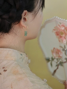 Macro shot of green aventurine stone earrings worn by a model in traditional style