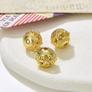 Three vintage hollow gold flower pattern beads for DIY jewelry making on white tray