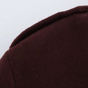 Gros plan sur la texture du tissu en laine bordeaux et les coutures du col de veste