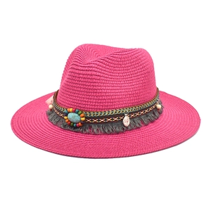 Detail of rose red straw hat featuring a bohemian ribbon with beads and turquoise stone