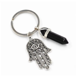 Macro shot of silver Hamsa hand charm and black crystal point pendant on key ring