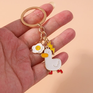 Detail of metal keychain featuring enamel white duck, fried egg, and lightning bolt charms