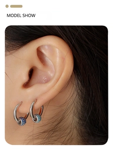 Close-up of silver hoop earrings with blue crystal-encrusted beads on a female model