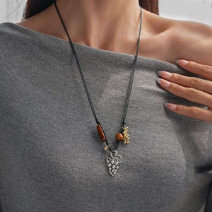 Détail d'un collier vintage avec pendentif raisin en argent et perles en bois