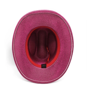 Detailed interior of glittery pink cowboy hat showing fabric labels and red strap