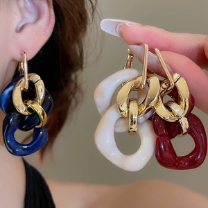 Macro detail of retro resin chain drop earrings in deep blue, cream, and wine red colors
