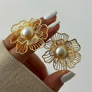 Detailed view of oversized hollow wire floral earrings with a large center pearl