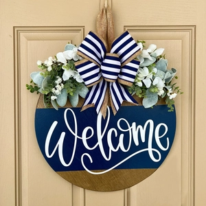 Detail of wooden welcome door hanger with blue-white striped bow and greenery